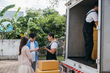 After furniture handling a satisfied couple signs the delivery checklist with the help of professional movers. Employee teamwork guarantees customer delight. Moving Day Concept