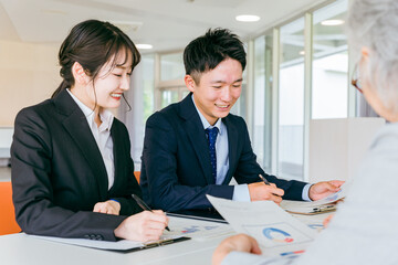 高齢者の相談を受けるスーツ姿の行政機関の男女（介護・医療・支援）
