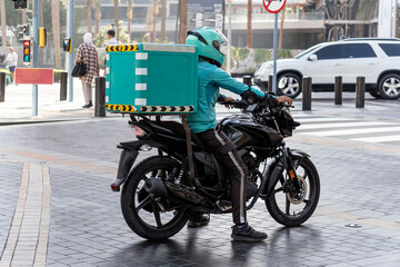 a food deliveryman is standing at a traffic light in green clothes. Photo of the delivery men driving motorcycle.