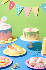 Birthday cakes are made from colored paper, gummy candies, marshmallows and cakes are displayed on round plates. Decorative ribbon. Birthday party concept.