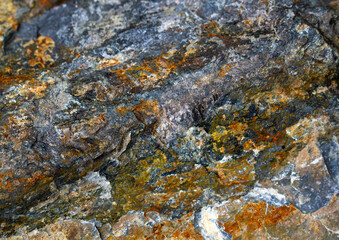 Colorful stone texture with yellow, blue, green and orange corrusion marks. Close up. Abstract background