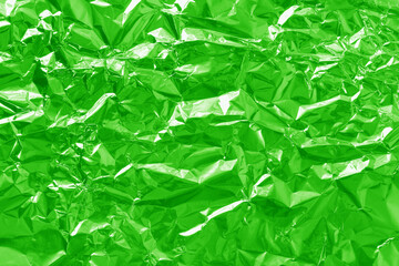 Fototapeta premium Shiny green lime foil texture background, pattern of wrapping paper with crumpled and wavy.