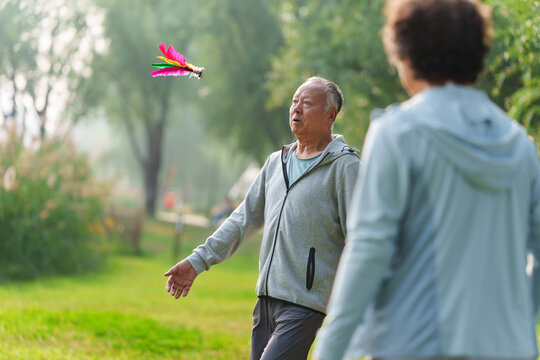 An elderly companion kicking shuttlecock on the grass