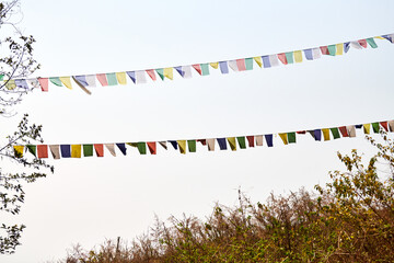 Colorful Tibetan prayer flags flutter ancient prayers into serene mountain wind at top of high hill...