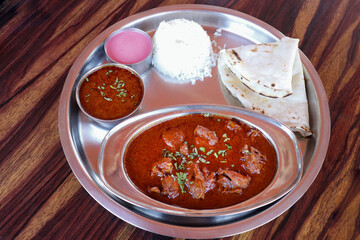 Malvani chicken Thali. It is a popular Indian or Konkani food platter that includes Chicken curry, egg curry, Rice bhakri, Steamed Rice, Solkadhi, and salad. Copy space.