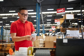 factory worker or warehouser counting money in the warehouse storage