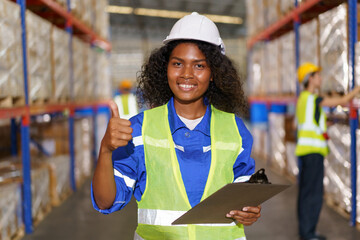 The photograph captures a mixed race-looking, fair-skinned female warehouse officer striking a confident pose for the camera inside the warehouse. - obrazy, fototapety, plakaty