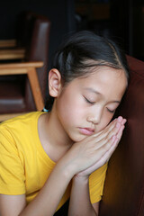 Close-up portrait of Asian girl child sleeping at sofa. Attractive lovely charming calm peaceful dreamy preteen kid lying and rest time indoors.