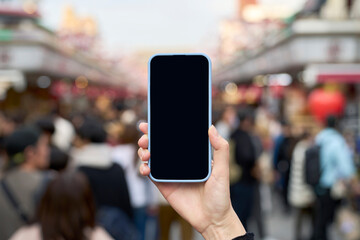 混雑する観光地とスマートフォンを持つ手