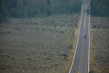 A person traveling on a three-wheeled motorcycle on a long tarmac road on a hot Summer day. Nr.2