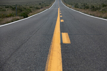 A wide highway road with yellow lines leading upward out of the frame
