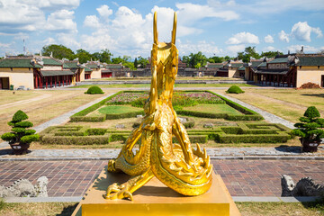 A golden statue overlooking a the gardens in the grounds of a temple at Hue in Vietnam