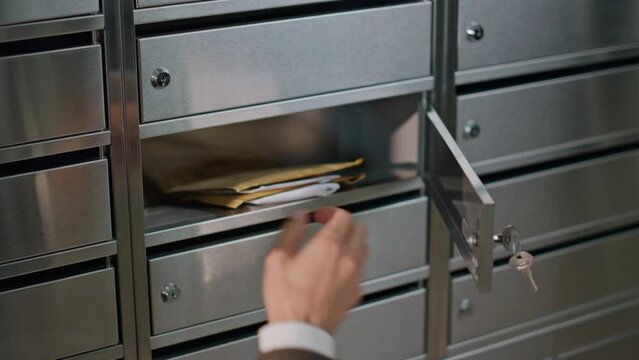 Closeup hand open mailbox in apartment building. Person in suit checking mail