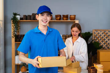 Portrait of delivery man hold the parcel box in his hand after picking up the item from the shopkeeper to deliver it to the customer. he looking at the camera in Small Business and Delivery Concept.