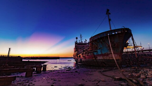 Time-lapse of rusty abandoned fishing boats with yellow colorful sunset reflected on the water, peaceful and serene picture, Taiwan, Asia

