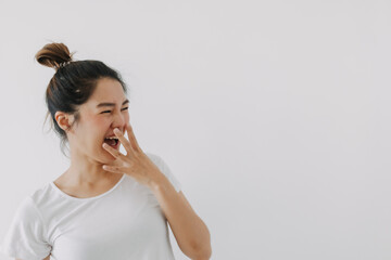 Happy asian Thai woman hand covering mouth while laughing, looking at empty space, feeling glad and joyful, wear white and bun hairstyle, standing isolated over white background wall. 