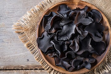 Wooden plate with dried jelly ear black mushrooms Auricularia auricula judae flat lay or top view