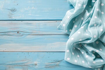 Folded light blue tablecloth with polka dots placed on a bleached wooden table in a top view image Ample space for your text - Powered by Adobe
