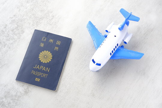 日本のパスポート（一般旅券5年用紺色）と飛行機のおもちゃで、海外旅行のイメージ
