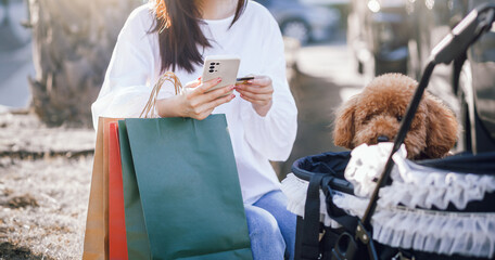 Young asian woman holding shopping bag after shopping in her holiday and use smart phone check...