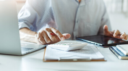 Close-up shot, businessmen or accountant using calculator calculate expenses and budget to planning and start new business and use a tablet to check orders from customers