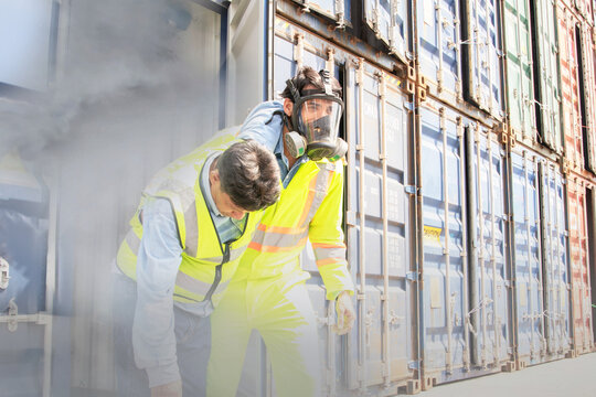 Male rescue workers PPE uniforms wearing gas mask protect against accidental leaks toxic fumes dangerous gases pungent odor keep workers unconscious safe from dangerous toxins inside container.