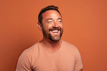 Portrait of a funny man laughing and looking at camera while standing against orange background