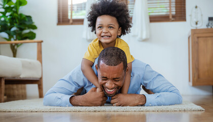Portrait of African father and son kissing laughing on living room floor. Daddy and little boy...