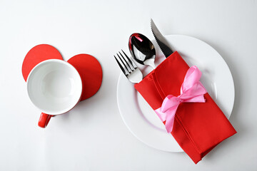 White plate and silverware of fork, knife, and spoon in red napkin