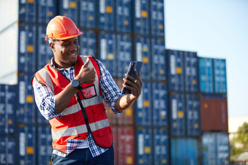 African factory worker or engineer holding tablet and video call to someone in containers warehouse...