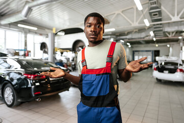 African man mechanic in uniform at the car repair station, portrait