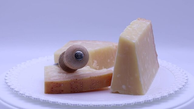 Italian Parmigiano Reggiano cheese with cheese knife rotating on a turntable. Parmesan cheese.