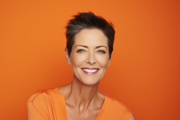 Beauty portrait of smiling middle aged woman on orange background. Attractive caucasian female looking at camera.