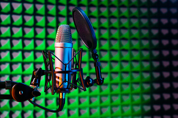 Professional studio microphone against acoustic foam panel background in neon light