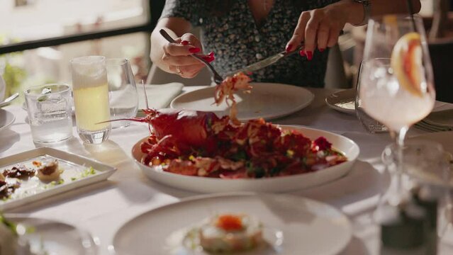 Woman Takes Lobster With Fork And Knife In Restaurant.