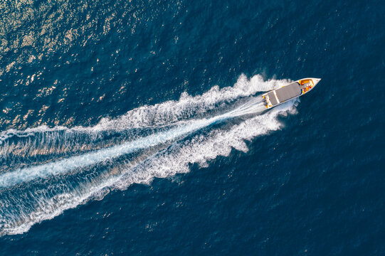 High speed boat rushing along the water surface of warm tropical waters, transfer of tourists. Aerial top view above