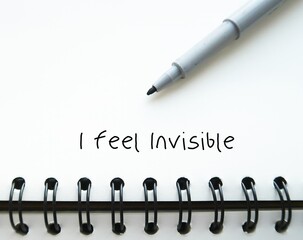Pen wrote on notebook I FEEL INVISIBLE - feeling ignored or overlooked by the people around - no...