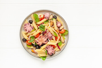 Penne pasta with vegetables and seafood in a plate on the table. Top View