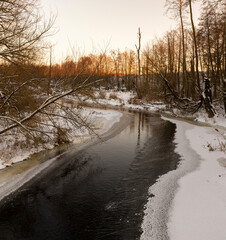 sunset on a river whose banks are covered with ice