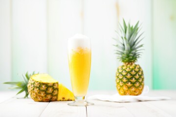 frothy pineapple beer in a tall glass with a pineapple side