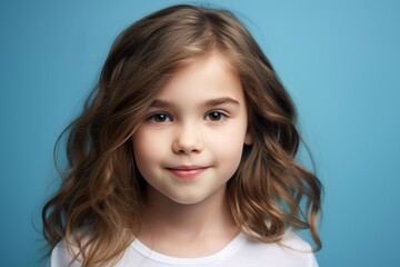 Portrait of a cute little girl with long curly hair on blue background