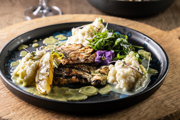 Grilled trout fillet with mashed potatoes and lemon sauce on a restaurant plate
