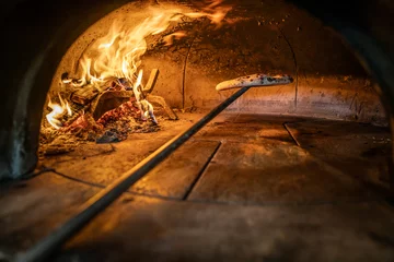 Fotobehang Traditional oven for baking pizza with burning wood and shovel. Neapolitan pizza is finished on a shovel in a brick oven © weyo