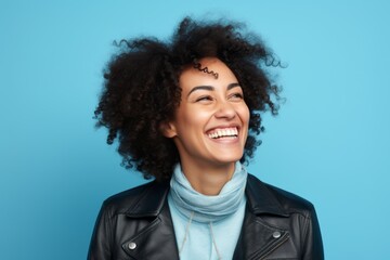Fototapeta na wymiar Cheerful african american woman in leather jacket on blue background