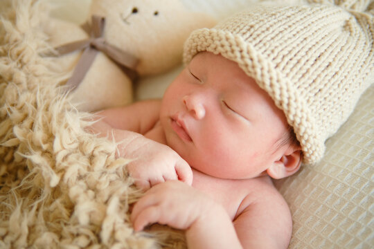 Close-up of newborn baby boy lying on with teddy bear and is covered with a brown cotton blanket. Portrait of a little child ten days old.