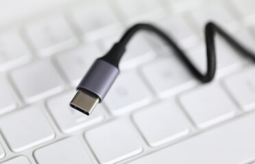 Close up, on computer keyboard cord with adapter. Usb input for tablet lies on keyboard....