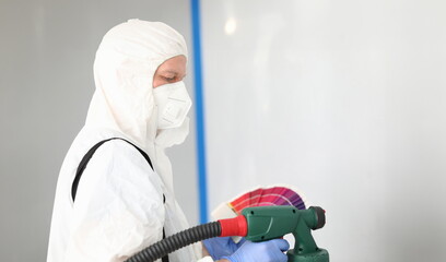 Builder in uniform chooses color for painting wall. Surface treated wall. Finishing putty to...