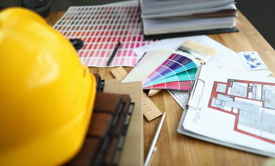 On table is apartment plan and protective helmet. Home renovation concept with comfort city...