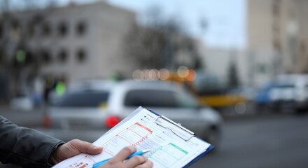 Man on street fills out an accident statement. Filling in by driver for subsequent transfer this...