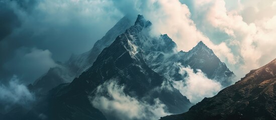 Mysterious minimalist high altitude picturesque mountain landscape with clouds touching large peaks and a spot of light on a mountain. Copy space image. Place for adding text or design